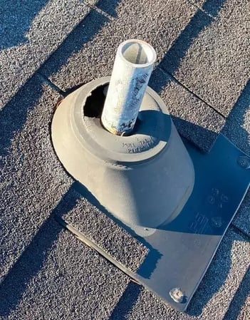 A dry rotted rubber pipe boot cracked around the base of a plumbing vent