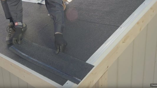 A roofer laying down a starter shingle