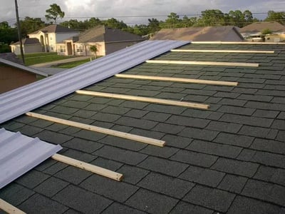 Metal being installed over asphalt shingles