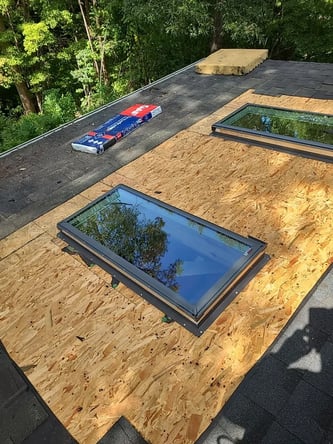 Newly installed skylights on an asphalt shingle roof
