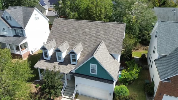 Completed charcoal shingle re-roof on a two-story home in Cary, NC — front elevation showing garage, dormers, and entry
