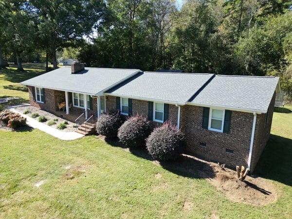 Completed light gray shingle re-roof on a brick ranch home in Garner, NC — full front and side elevation