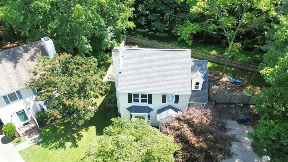 Completed Pewter Gray GAF HDZ shingle roof on a white two-story Raleigh home on a wooded lot on Kempsford Pl