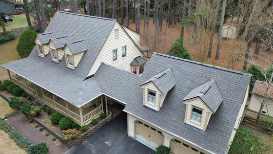 Charcoal GAF HDZ shingles on a cream two-story Raleigh home with four shed-roof dormers on The Dyke Drive