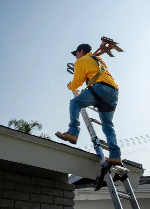 On Tops crew member climbing onto a roof for a repair inspection