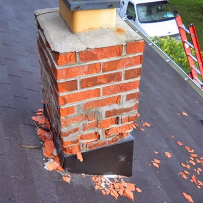 A chipped, damaged brick chimney.