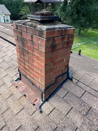 Brick chimney penetrating an asphalt shingle roof