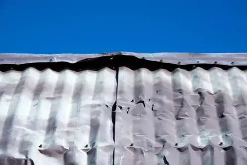 A dented and damaged metal roof