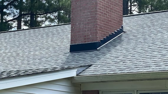 Metal step flashing along a roof and wall intersection