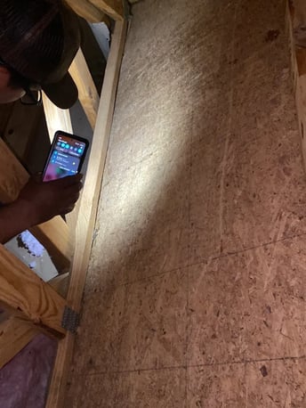 Inspecting an attic with a flashlight while looking for a roof leak