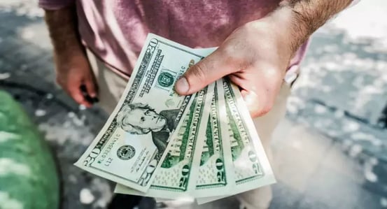 man in red shirt handing over 4 $20 bills