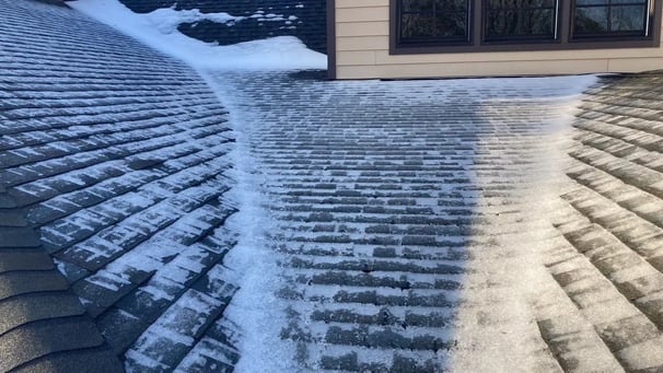 Snow melting and running down a shingle roof toward the eaves