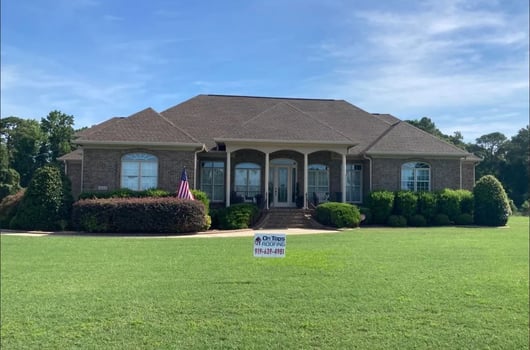 Newly installed asphalt shingle roof with an On Tops Roofing yard sign