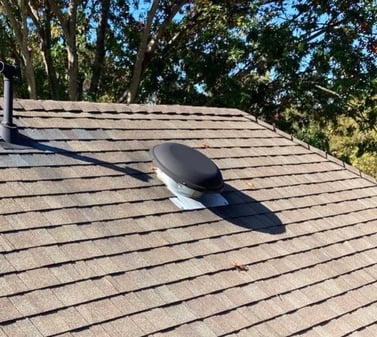 Powered attic vent with a fan mounted on a roof
