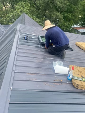 Roofer working on a roof near a skylight opening