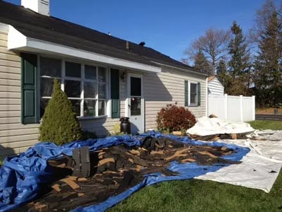 garden covered with blue tarp that's holding leftover roofing debris