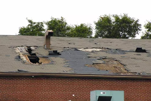 A weather-damaged roof with holes and missing shingles