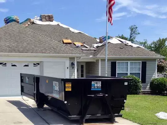 A dumpster in front of a house getting roof repairs
