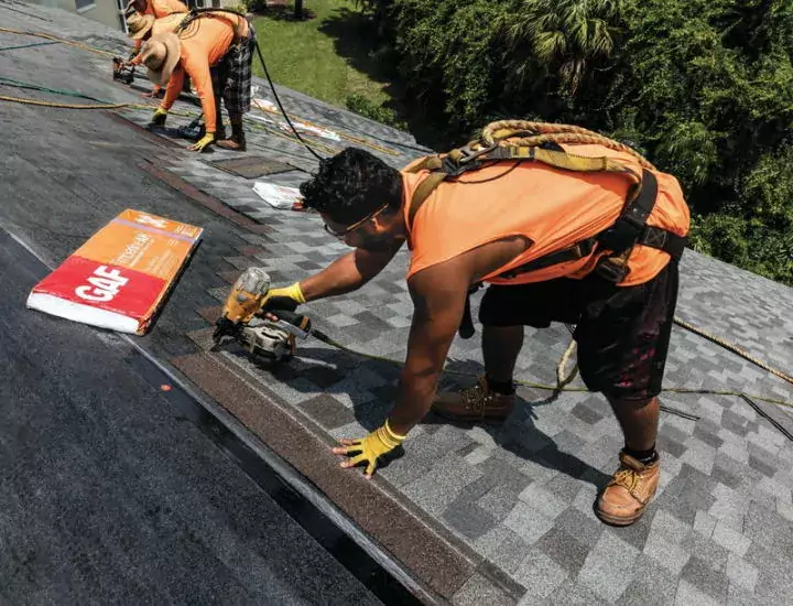 Several roofers installing an asphalt shingle roof