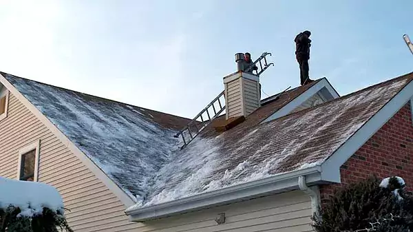 Two roofers on a snowy winter roof