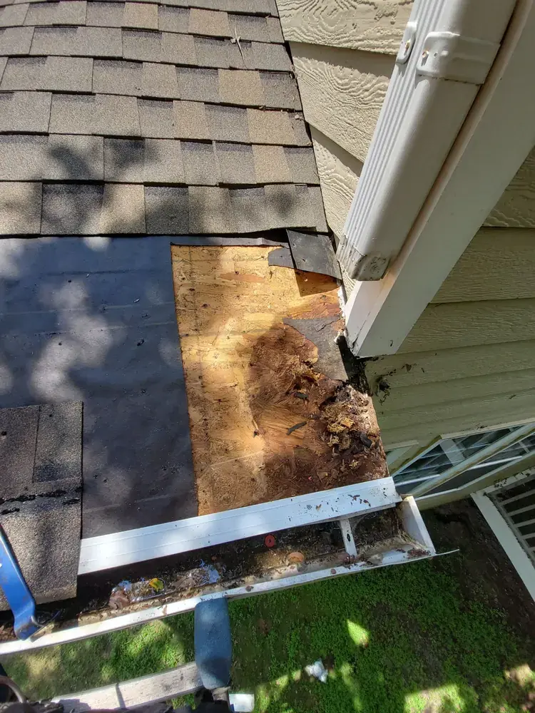 Rotted roof decking at downspout area showing water damage and wood deterioration