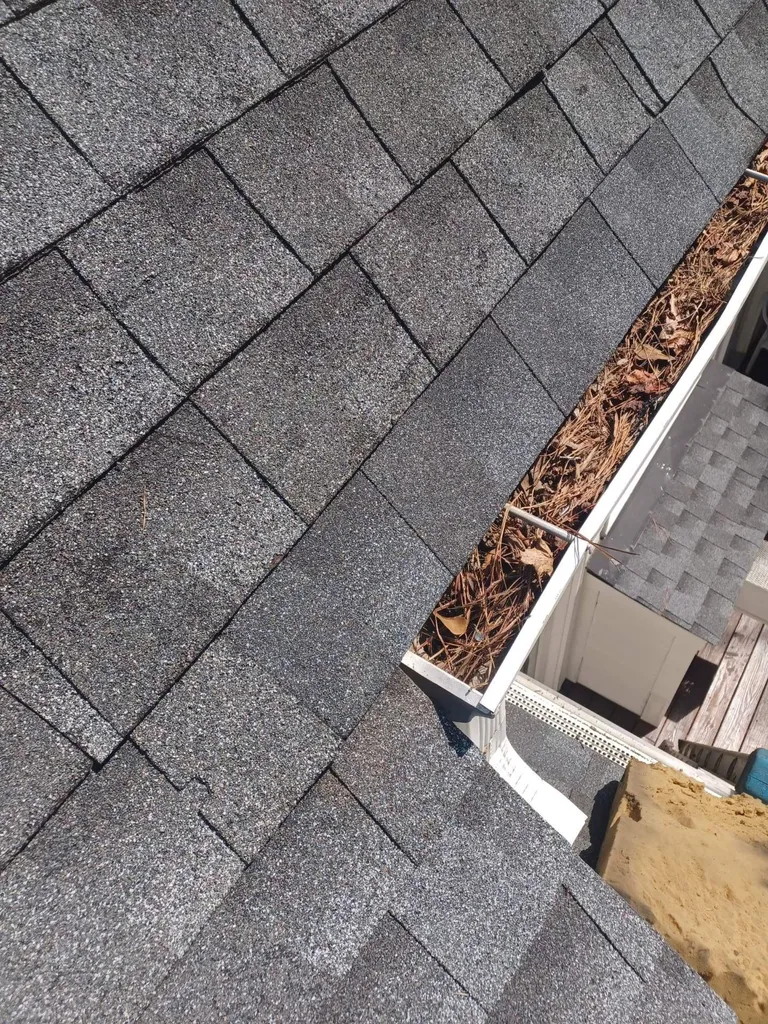 A roof gutter packed with wet leaves and tree debris
