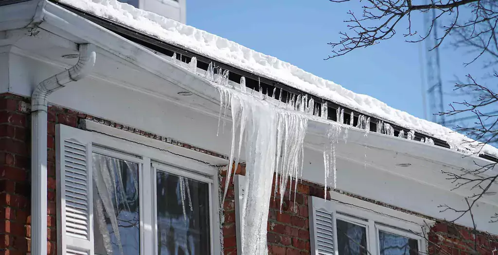 Ice dams forming on the edge of a roof, and weighing down the gutter