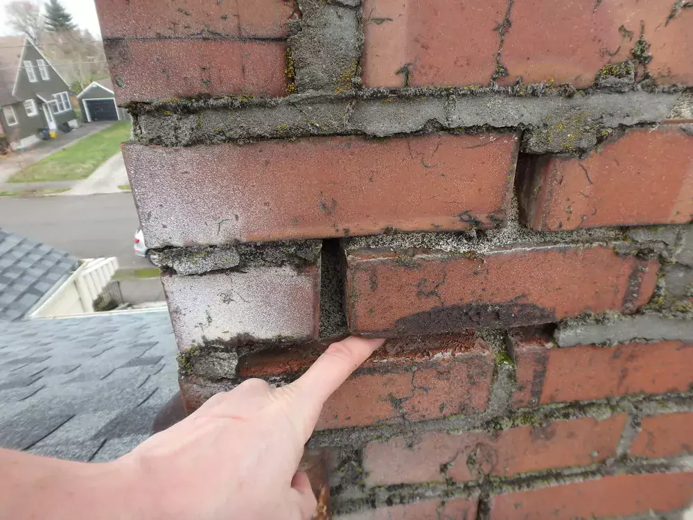 finger pointing at crumbled chimney mortar