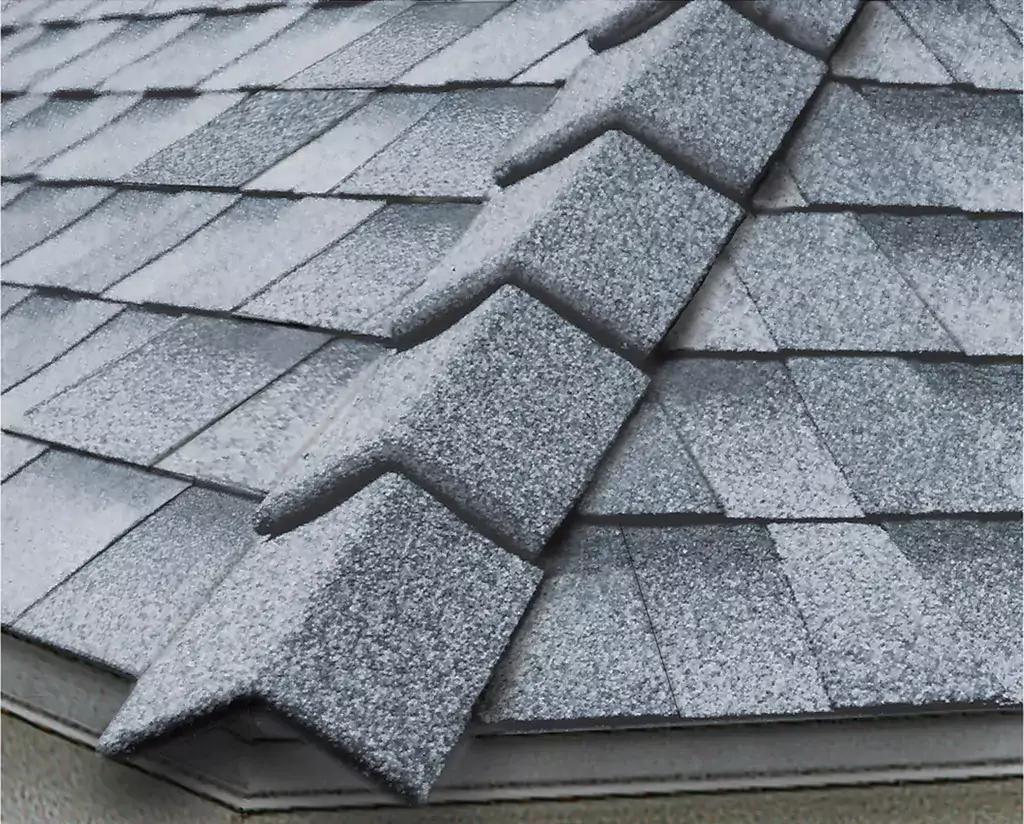 ridge cap shingles going down the side of a gray shingle roof