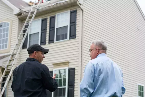 two men discussing roofing in front of a home